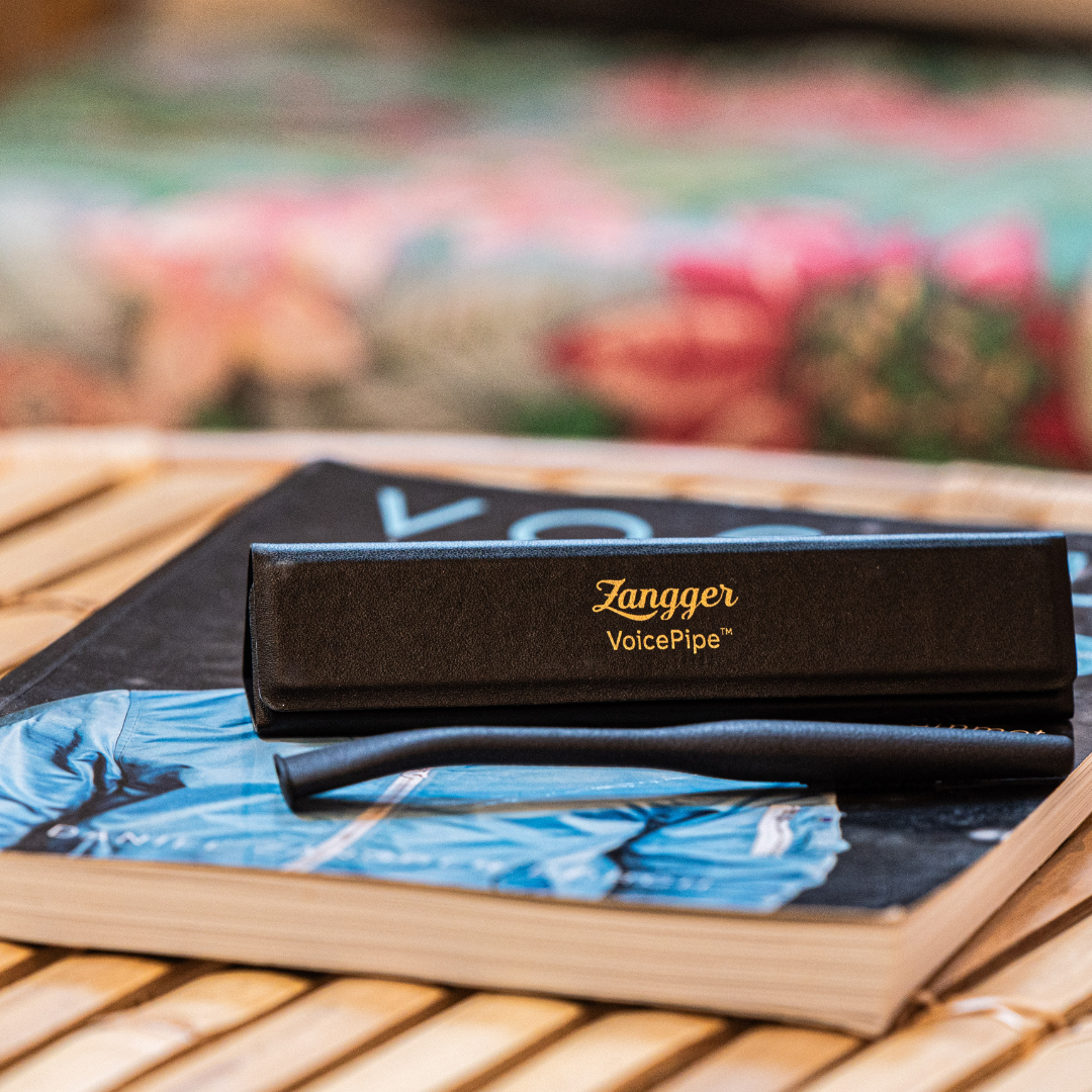 Zangger VoicePipe and its black case with gold logo, resting on the Vocal Workout of the Day book