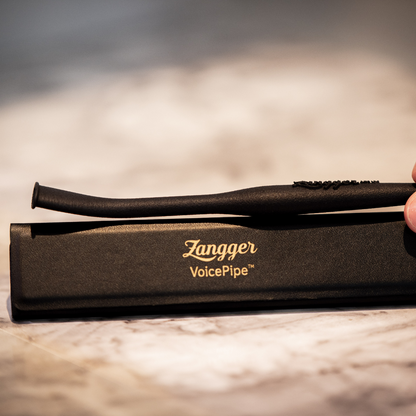 Hand holding the Zangger VoicePipe above its open case, showing the full tapered length of the tube